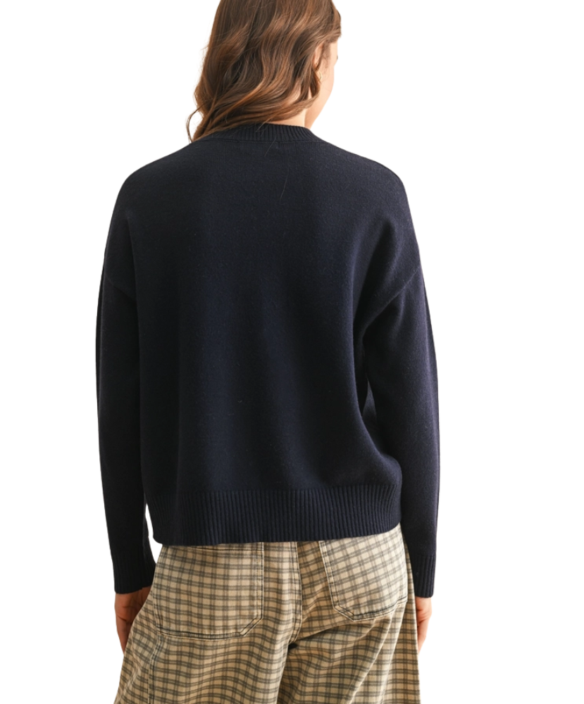 Person wearing a navy sweater and plaid pants on a white background