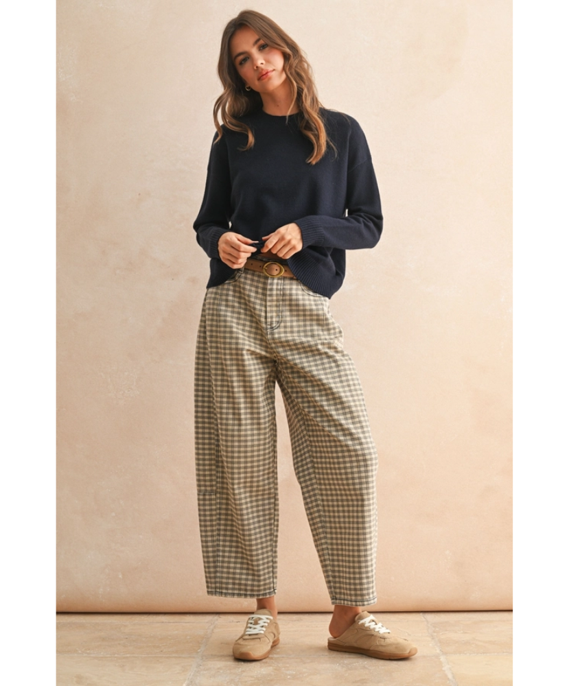 Woman wearing a navy sweater and plaid pants against a beige wall.