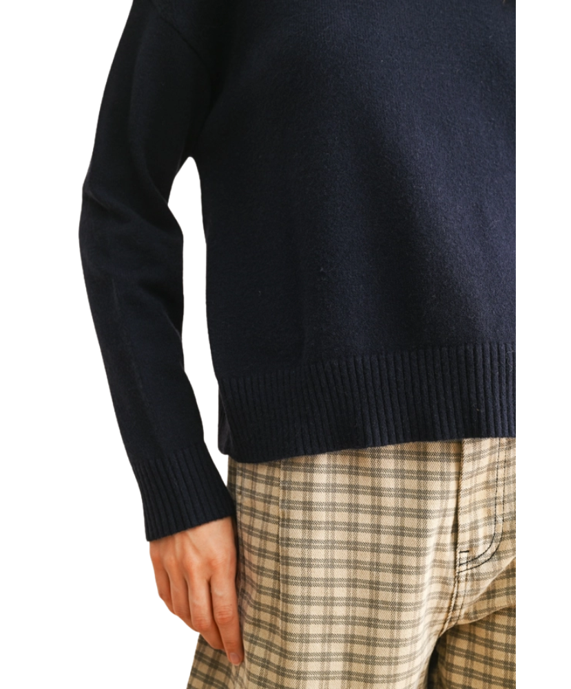 Navy sweater worn by a person with plaid pants on a white background