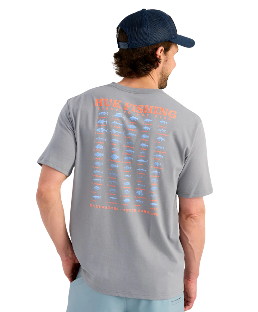 Man wearing a gray t-shirt with fishing-themed design on the back, standing against a white background.