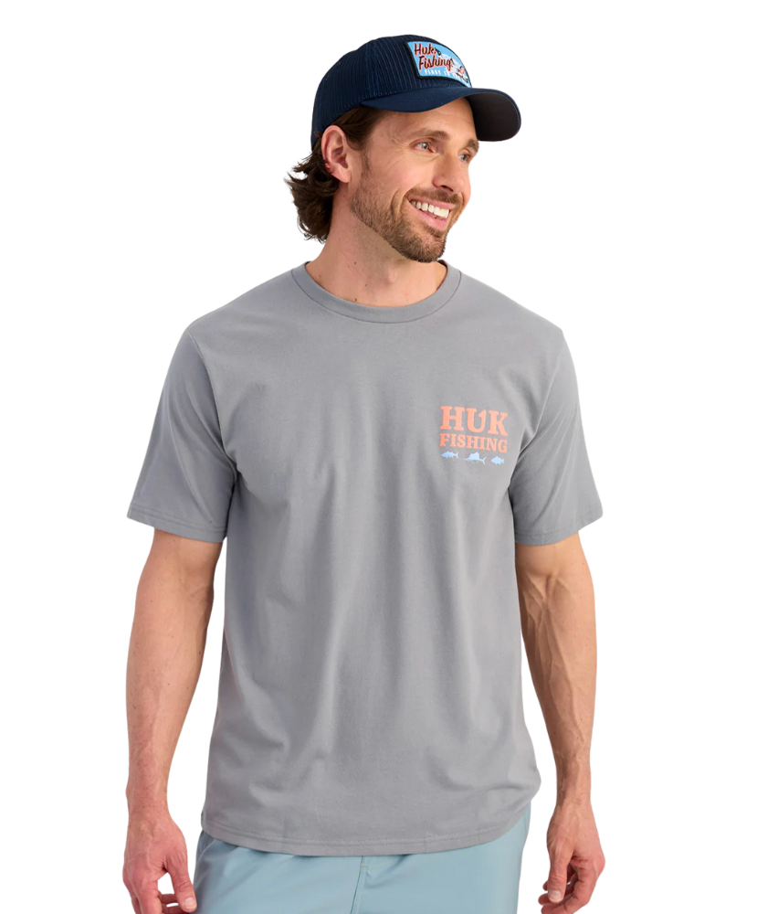 Man wearing a gray t-shirt with branding and a navy cap on a white background