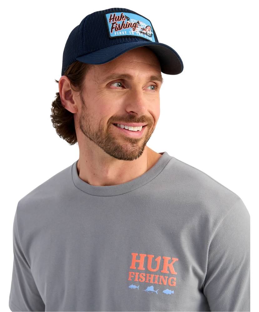 Man wearing a navy cap and gray shirt with 'Huk Fishing' logo on a white background