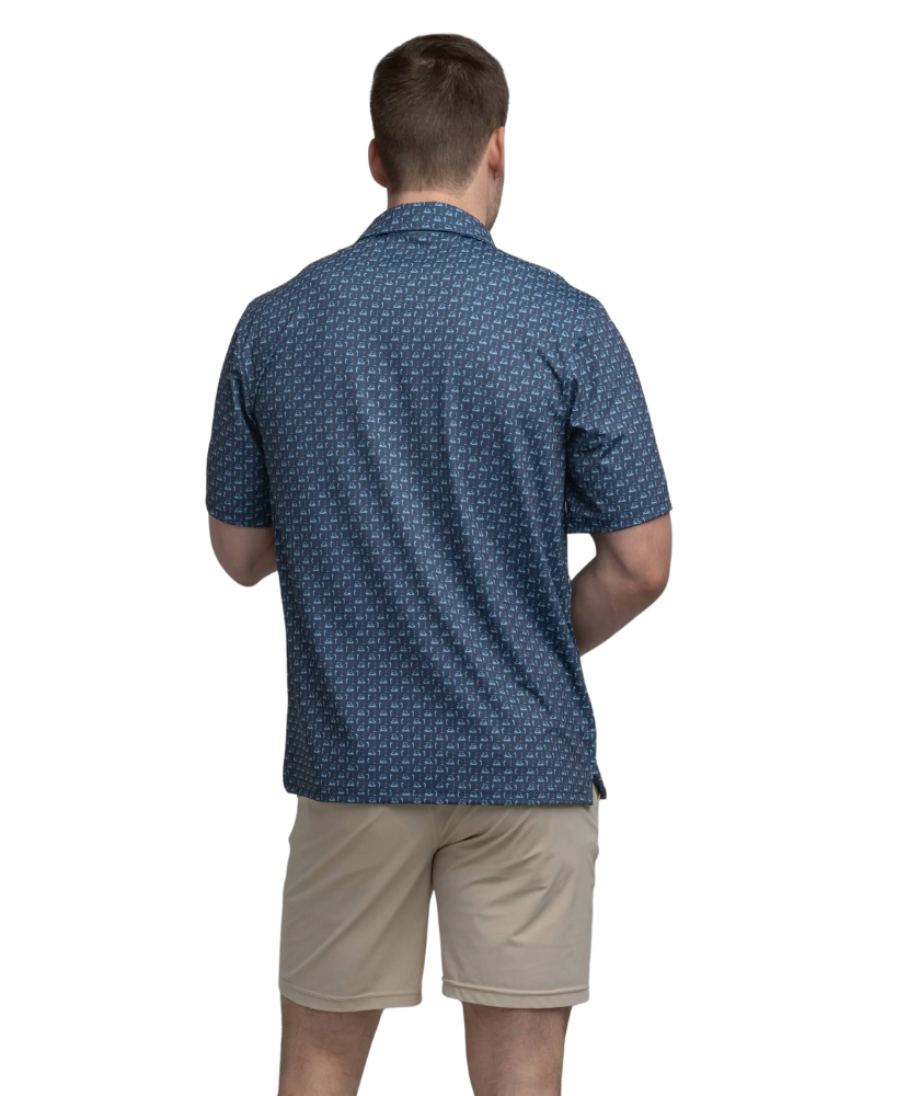 Man wearing a blue golf cart patterned polo shirt and beige shorts on a white background