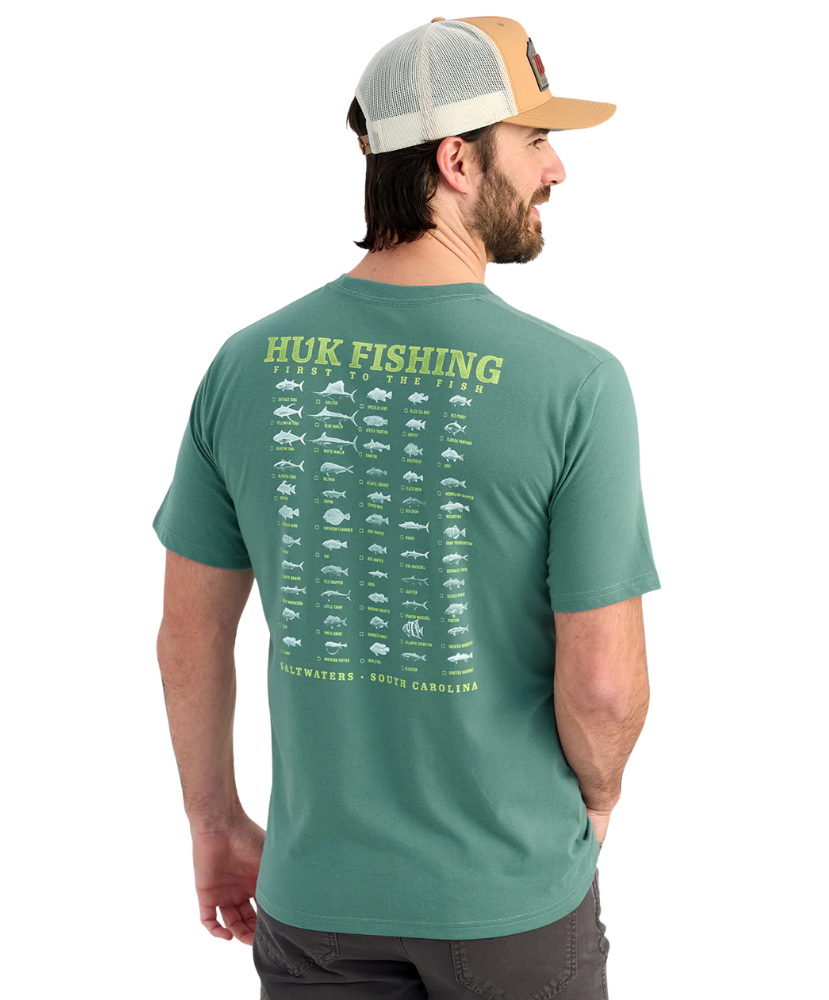 Man wearing a green Huk Fishing t-shirt with fish illustrations on the back.