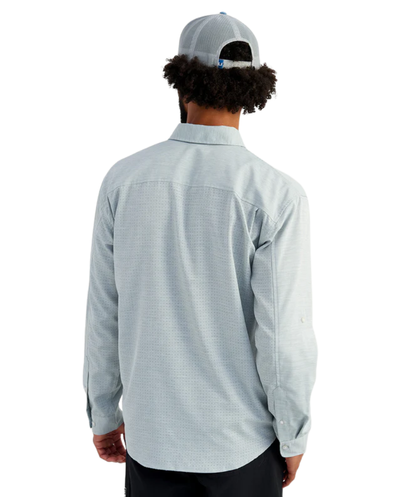 Man wearing a light blue HUK button-up shirt and blue cap on a white background