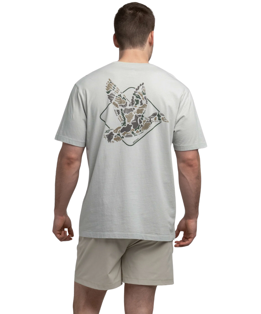 Man wearing a light gray t-shirt with a graphic design on the back, standing against a white background.