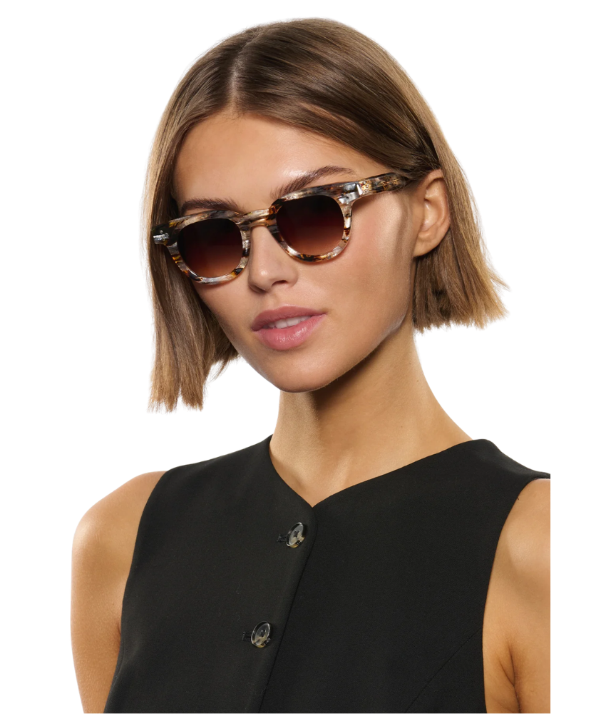 Woman wearing Krewe sunglasses with a neutral background