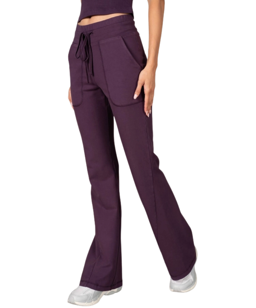 Woman wearing a purple tank and pants athleisure set outfit on a white background