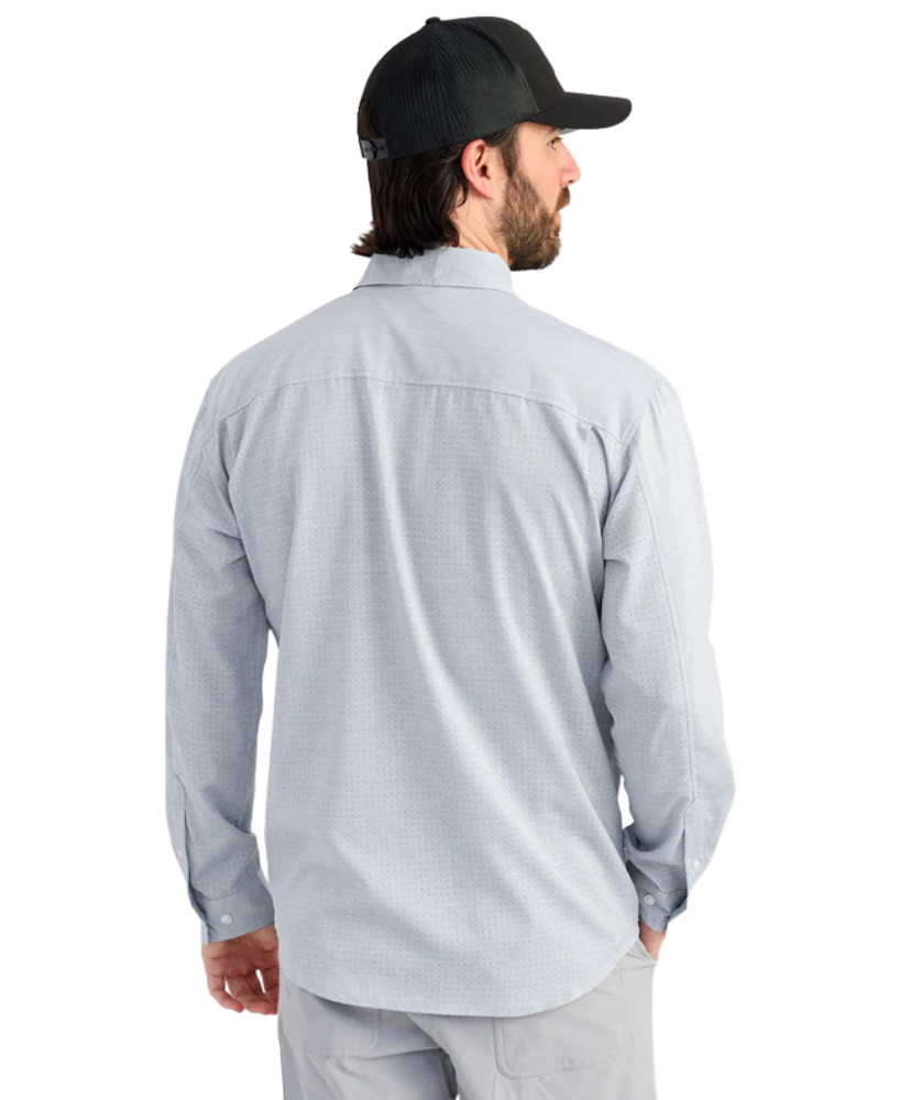 Man wearing a light blue performance HUK button-up shirt and black cap on a white background