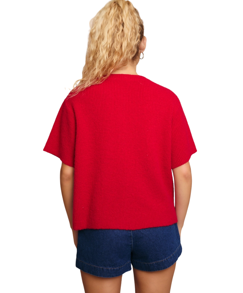 Woman wearing a red cardigan sweater and blue shorts on a white background