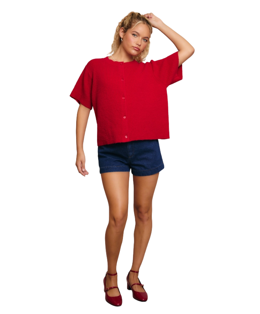 Woman wearing a red cardigan sweater and blue shorts on a white background