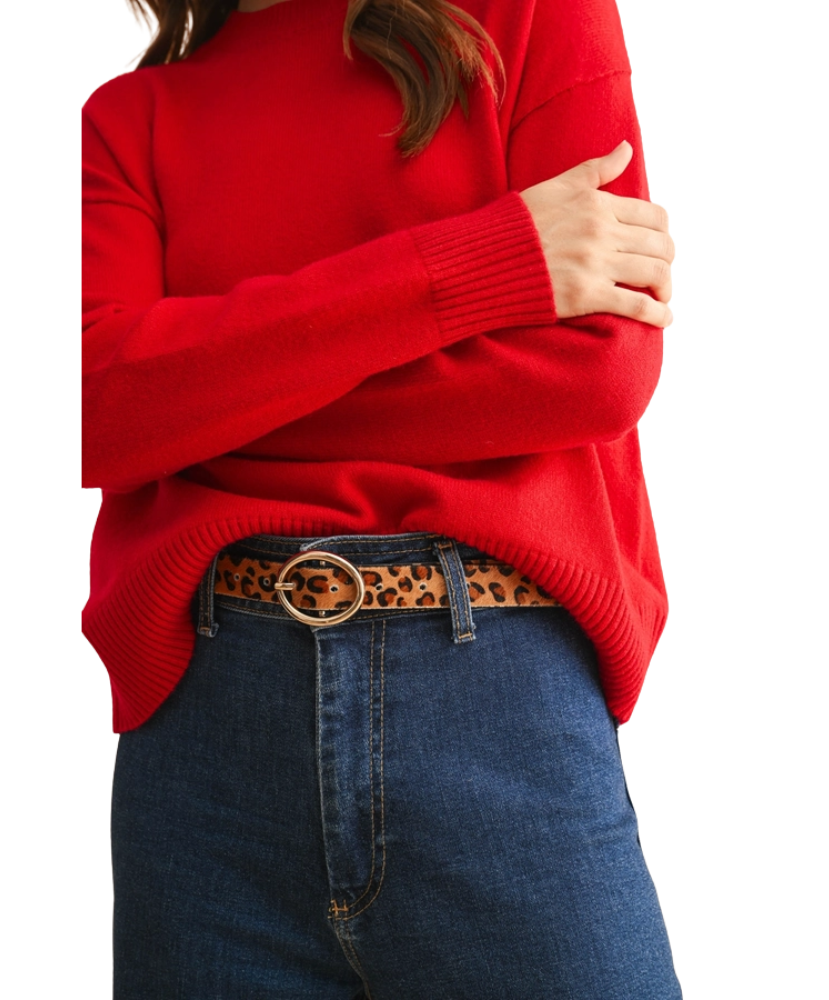 Person wearing a red sweater and blue jeans with a leopard print belt on a white background
