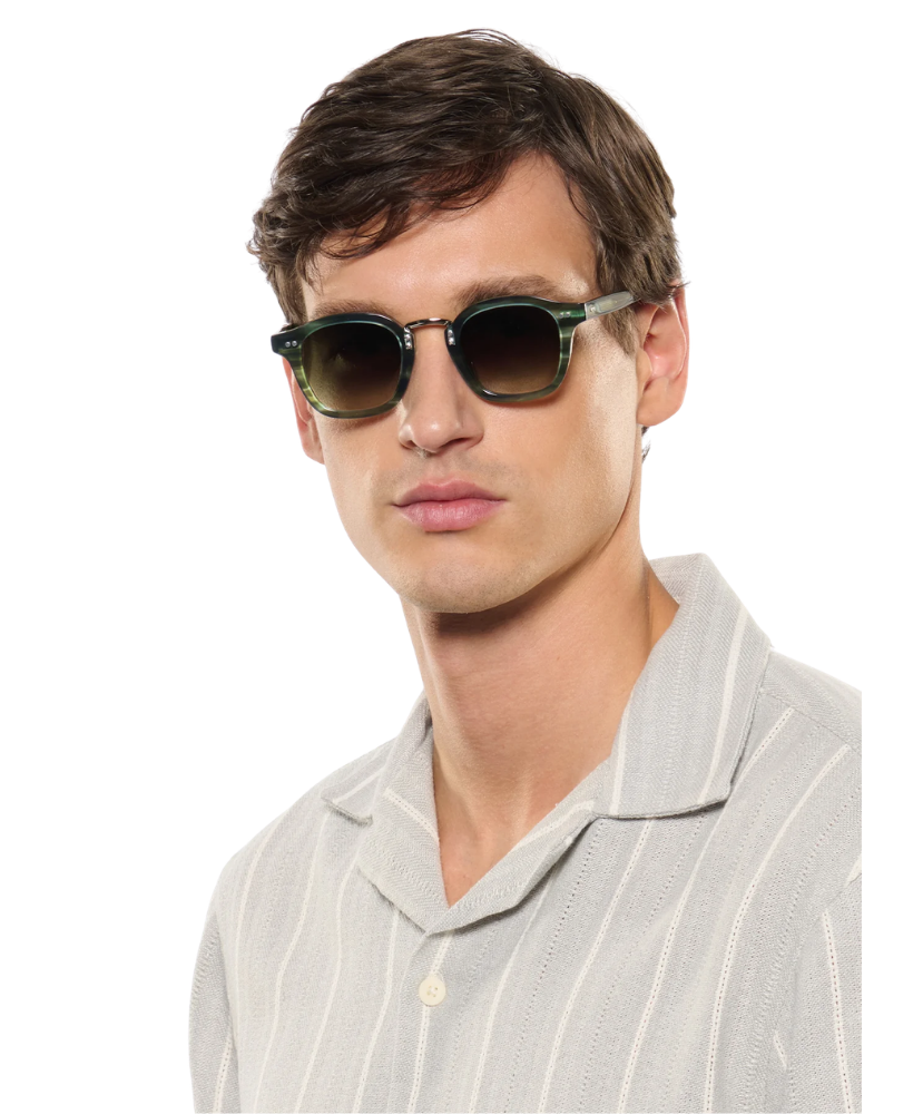 Man wearing krewe sunglasses and a light gray shirt on a white background