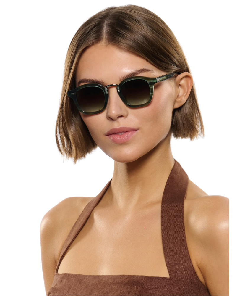 Woman wearing Krewe sunglasses with a plain background