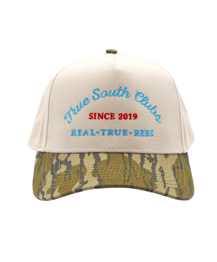 Beige cap with camouflage bill and embroidered text on a white background