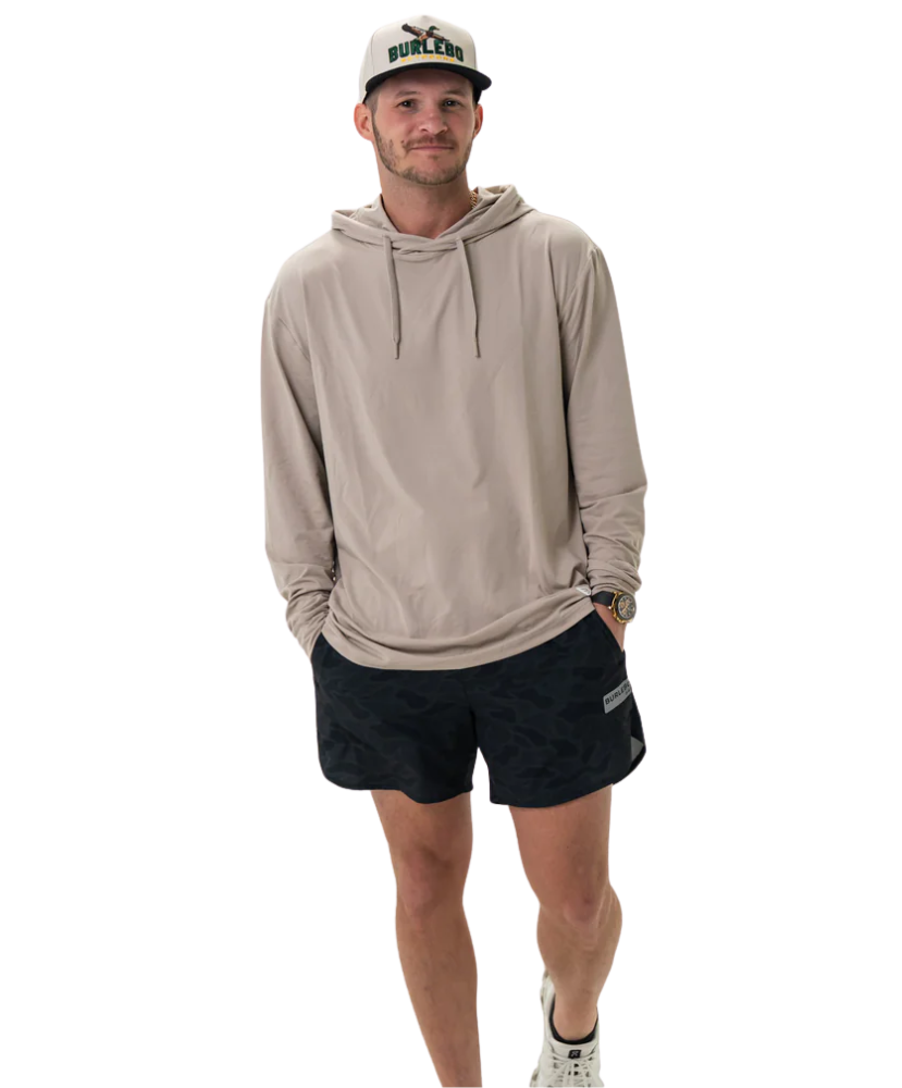 Man wearing a beige hoodie and black shorts on a white background