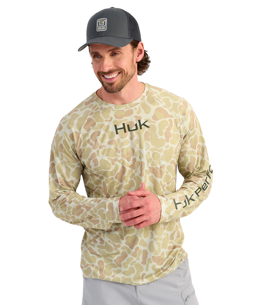 Man wearing a camouflage long-sleeve shirt with 'HUK' branding on a white background