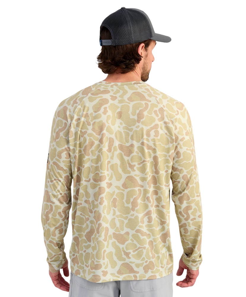 Man wearing a long-sleeve camouflage shirt and cap on a white background