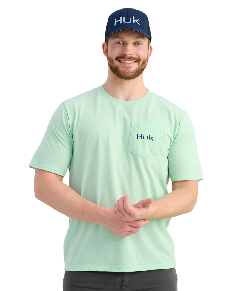 Man wearing a light green Huk shirt and cap on a white background