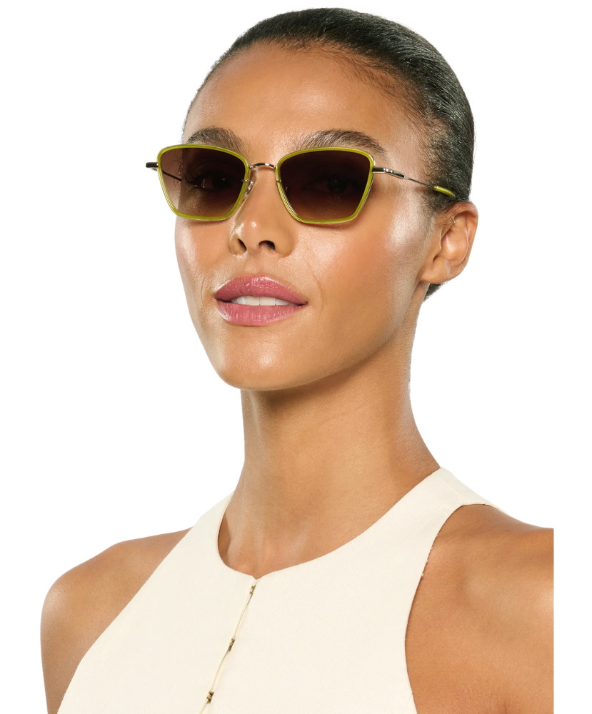 Woman wearing Krewe sunglasses with a plain background