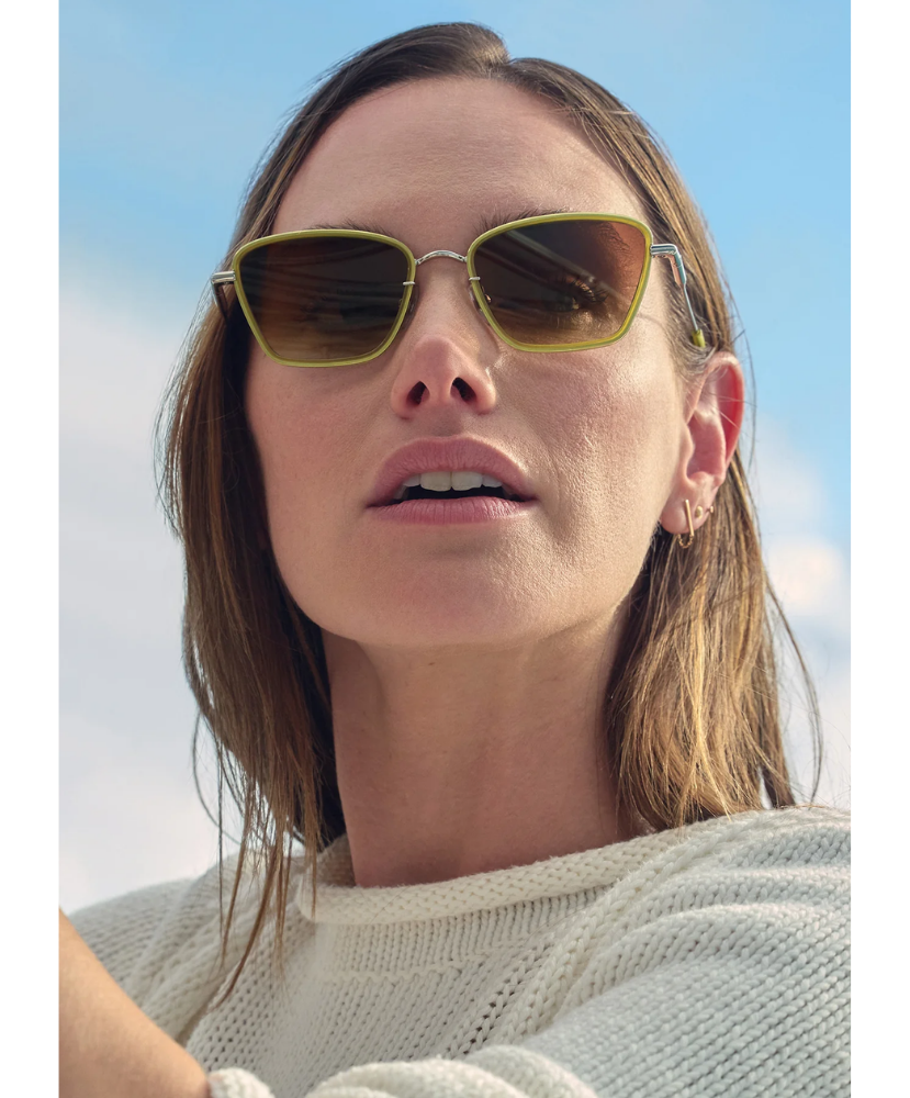 Woman wearing Krewe sunglasses with a plain background