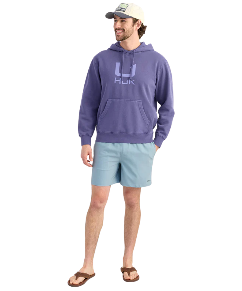 Man wearing a BLUE purple hoodie with a HUK logo, standing against a white background