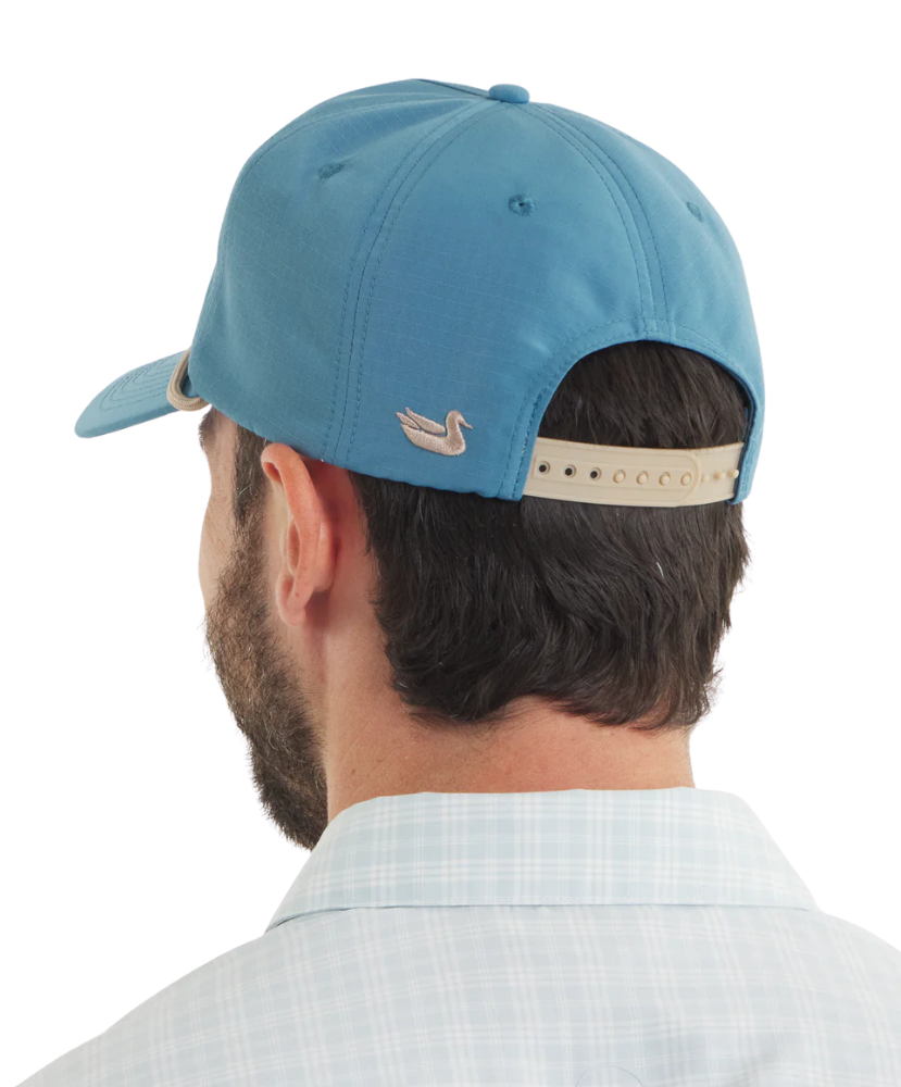 Man wearing a blue cap with a logo on the back against a white background