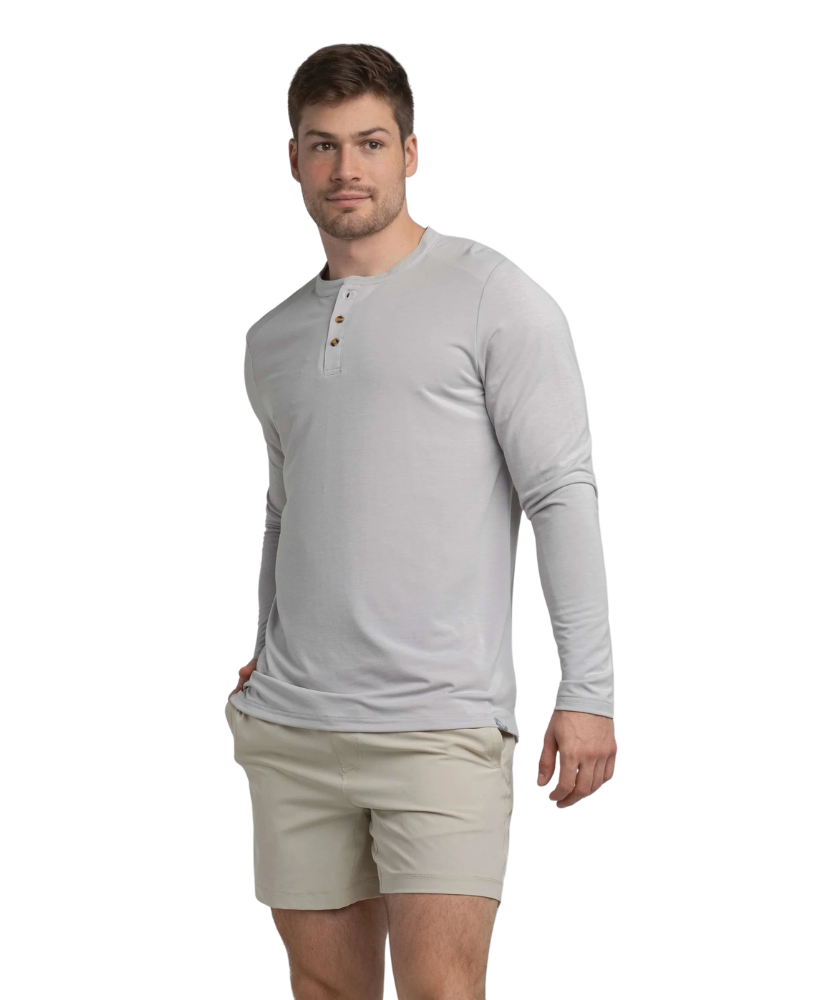 Man wearing a light gray long-sleeve henley shirt and beige shorts on a white background