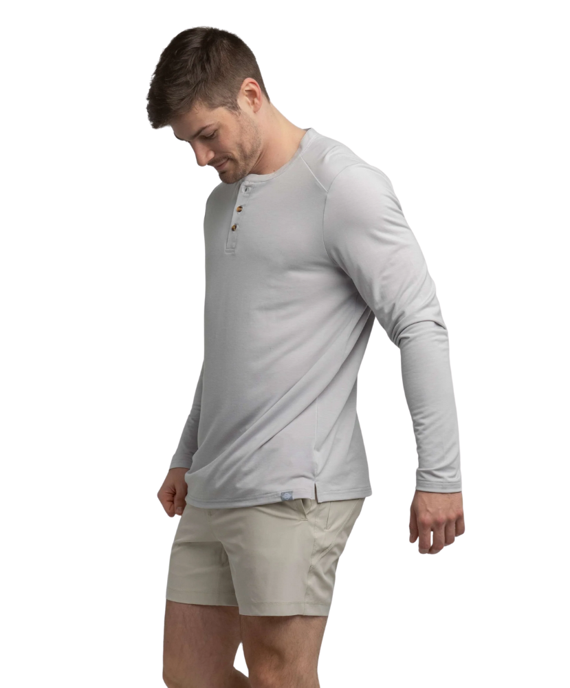 Man wearing a light gray long-sleeve henley shirt and beige shorts on a white background