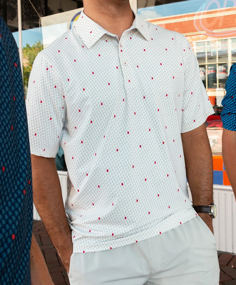 Man wearing a white polo shirt with red Alabama state outline pattern and 'SSCO' logo on a white background and light shorts on a white background