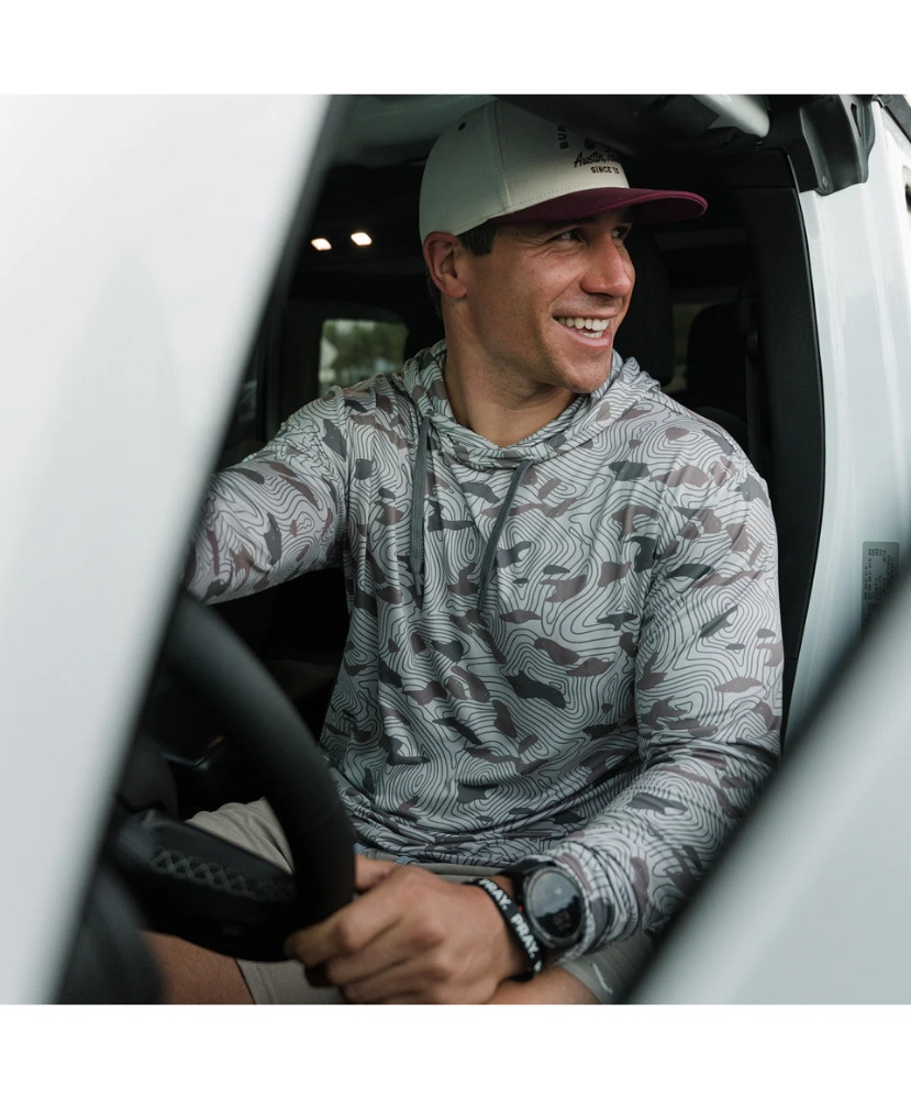 Man sitting inside a vehicle wearing a camouflage-patterned BURLEBO hoodie