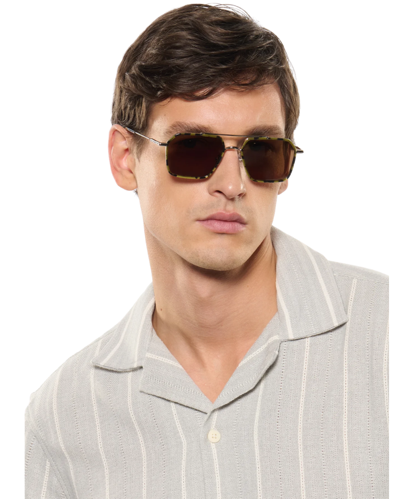 Man wearing Krewe sunglasses and a light gray shirt on a white background