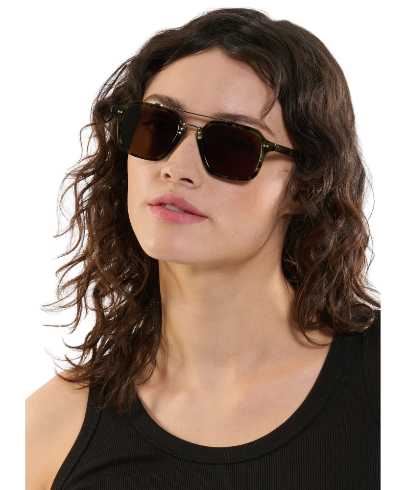 Woman wearing dark sunglasses with a plain background