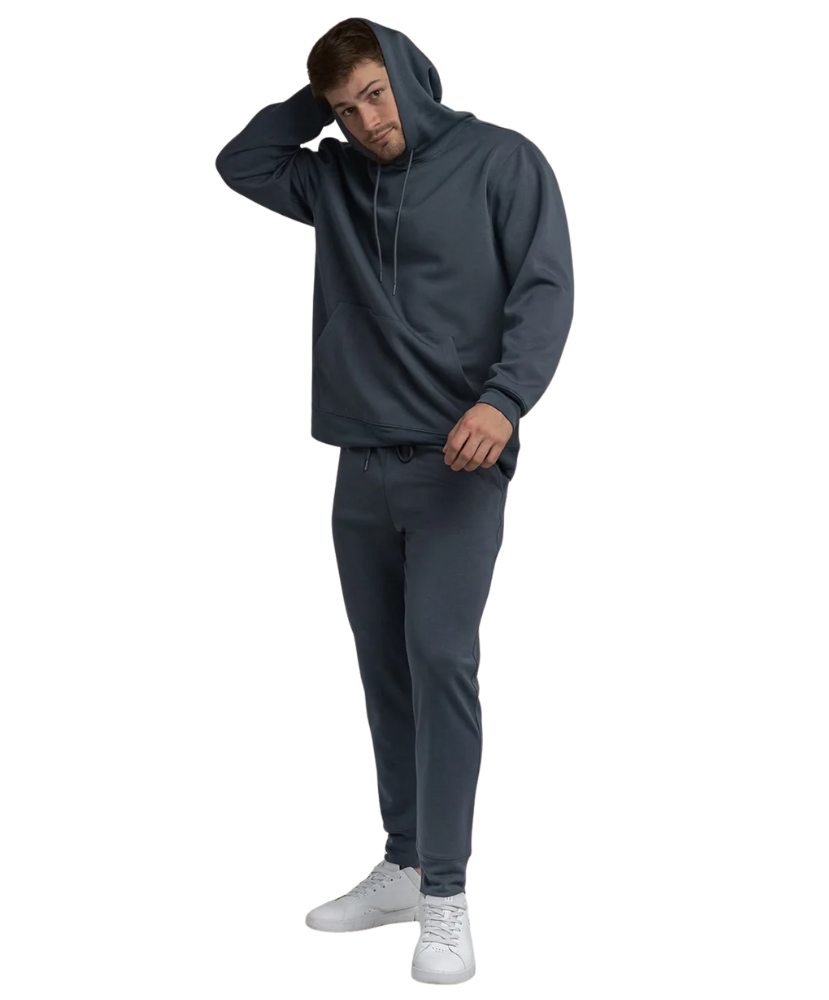 Man wearing a blue hoodie and pants with white sneakers on a white background