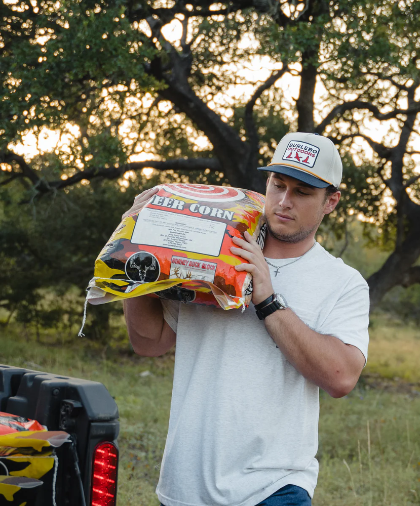 Man wearing a Burlebo Outdoors cap in an outdoor setting with trees in the background
