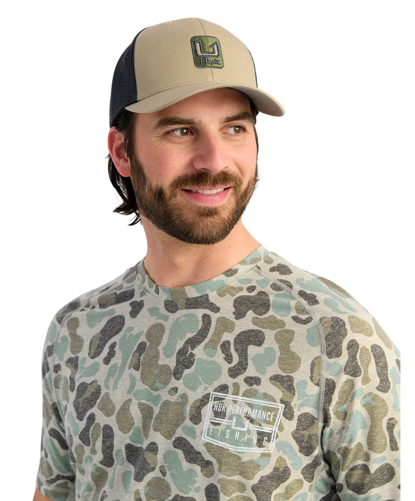 Man wearing a camouflage t-shirt and cap with a logo on a white background