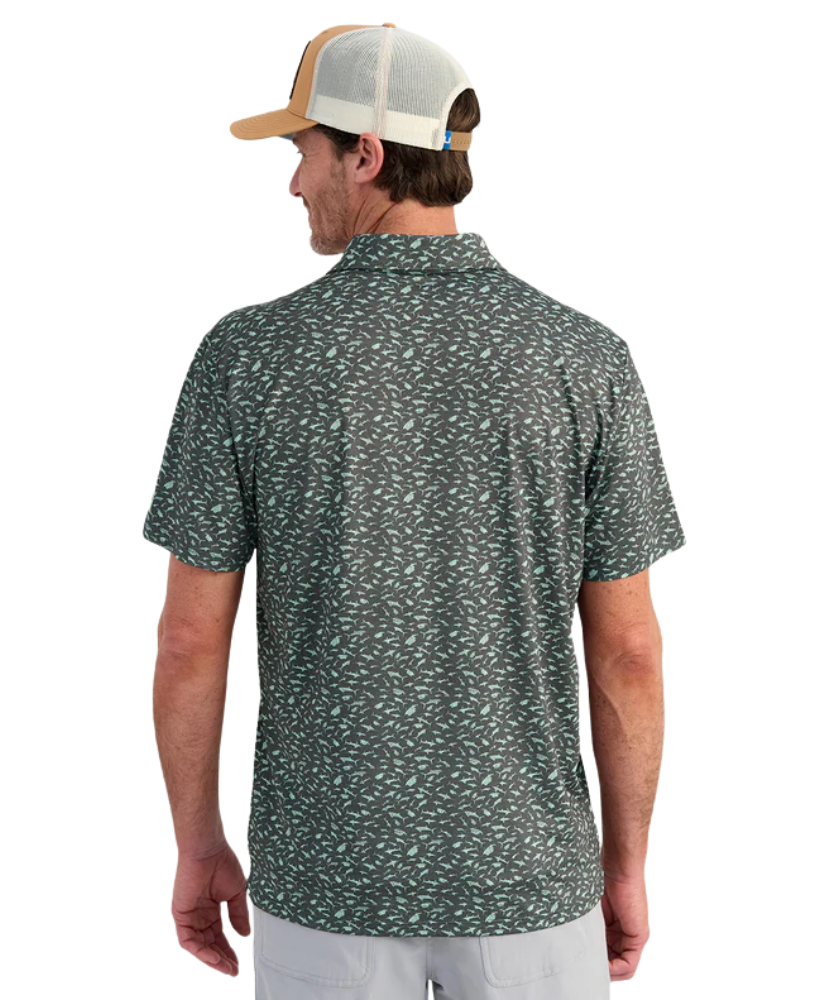 Man wearing a patterned polo shirt and cap on a white background