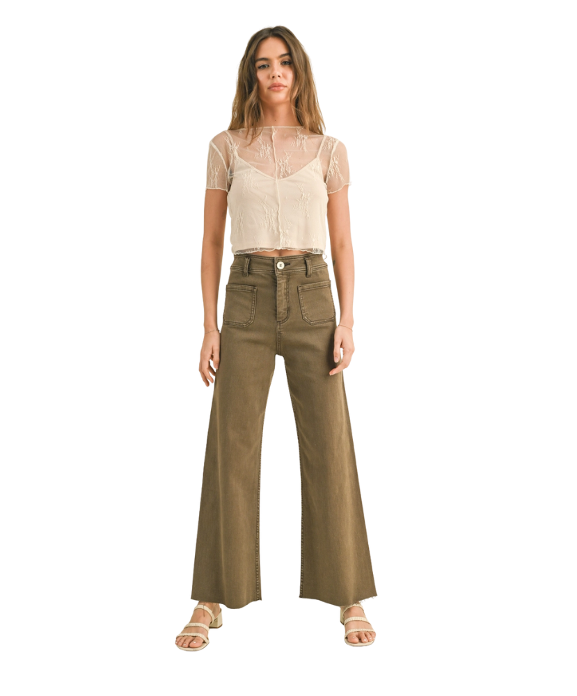Woman wearing a beige top and olive green wide-leg pants on a white background