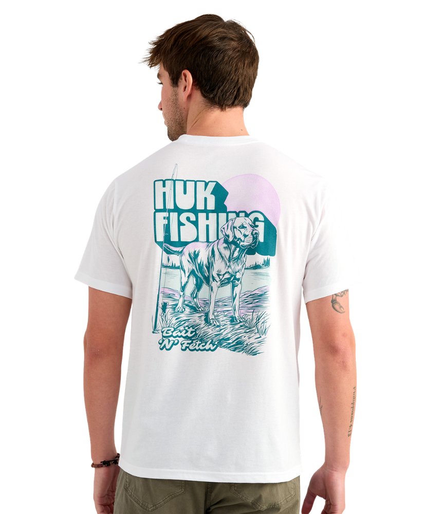 Man wearing a white Huk Fishing t-shirt with a graphic of a dog on the back.