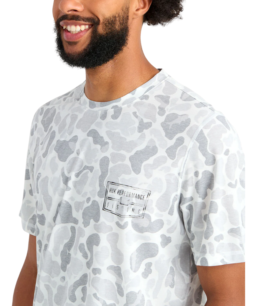 Man wearing a white camouflage t-shirt with a brand logo on a white background