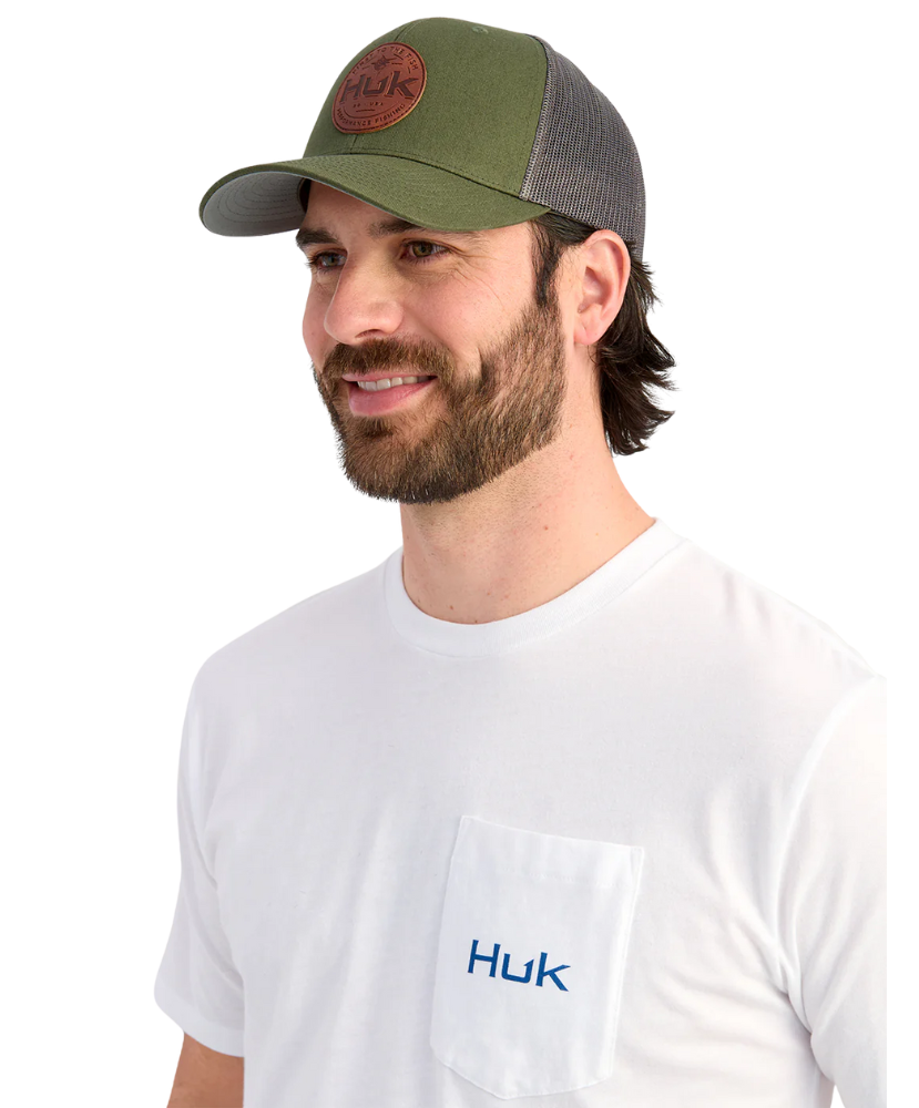 Man wearing a green and gray cap and white Huk shirt on a white background