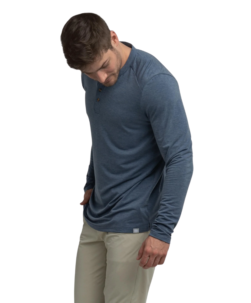 Man wearing a blue long-sleeve henley shirt and beige pants on a white background