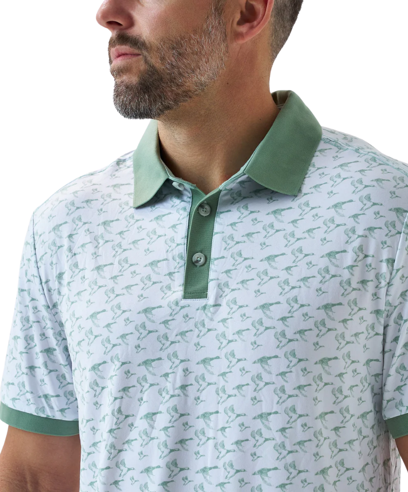 Man wearing a white duck and waterfowl patterned polo shirt with green accents on a white background