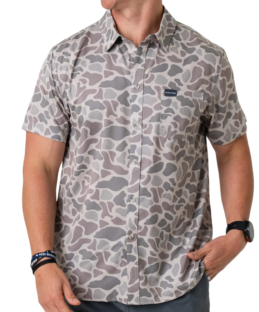 Person wearing a camouflage-patterned button-down shirt with a visible brand logo on a white background