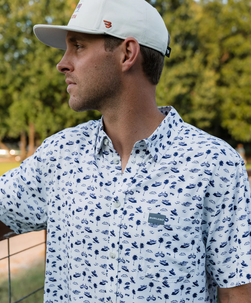 Man wearing a white short-sleeve button down shirt with a blue coastal pattern on a white background