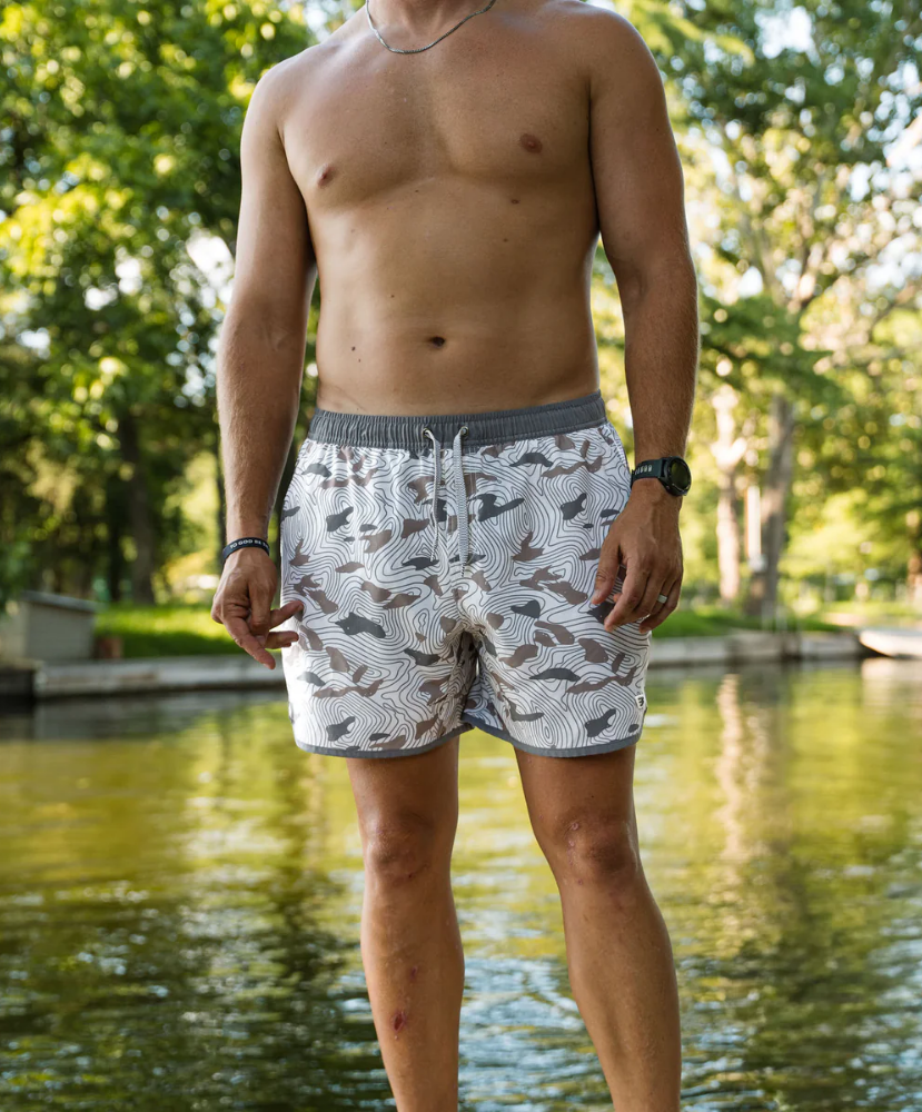 Person wearing camouflage swim shorts on a white background