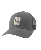 A dark gray trucker hat with a curved brim, featuring a front patch logo that reads 'HUK' and a mesh back.