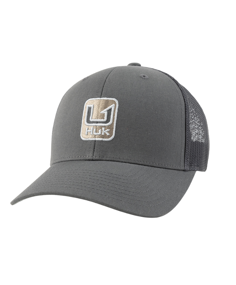 A dark gray trucker hat with a curved brim, featuring a front patch logo that reads 'HUK' and a mesh back.