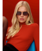 Woman wearing KREWE sunglasses and a red sweater against a red background