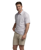 Man wearing a transfusion patterned Southern Shirt Co polo shirt and beige shorts on a white background